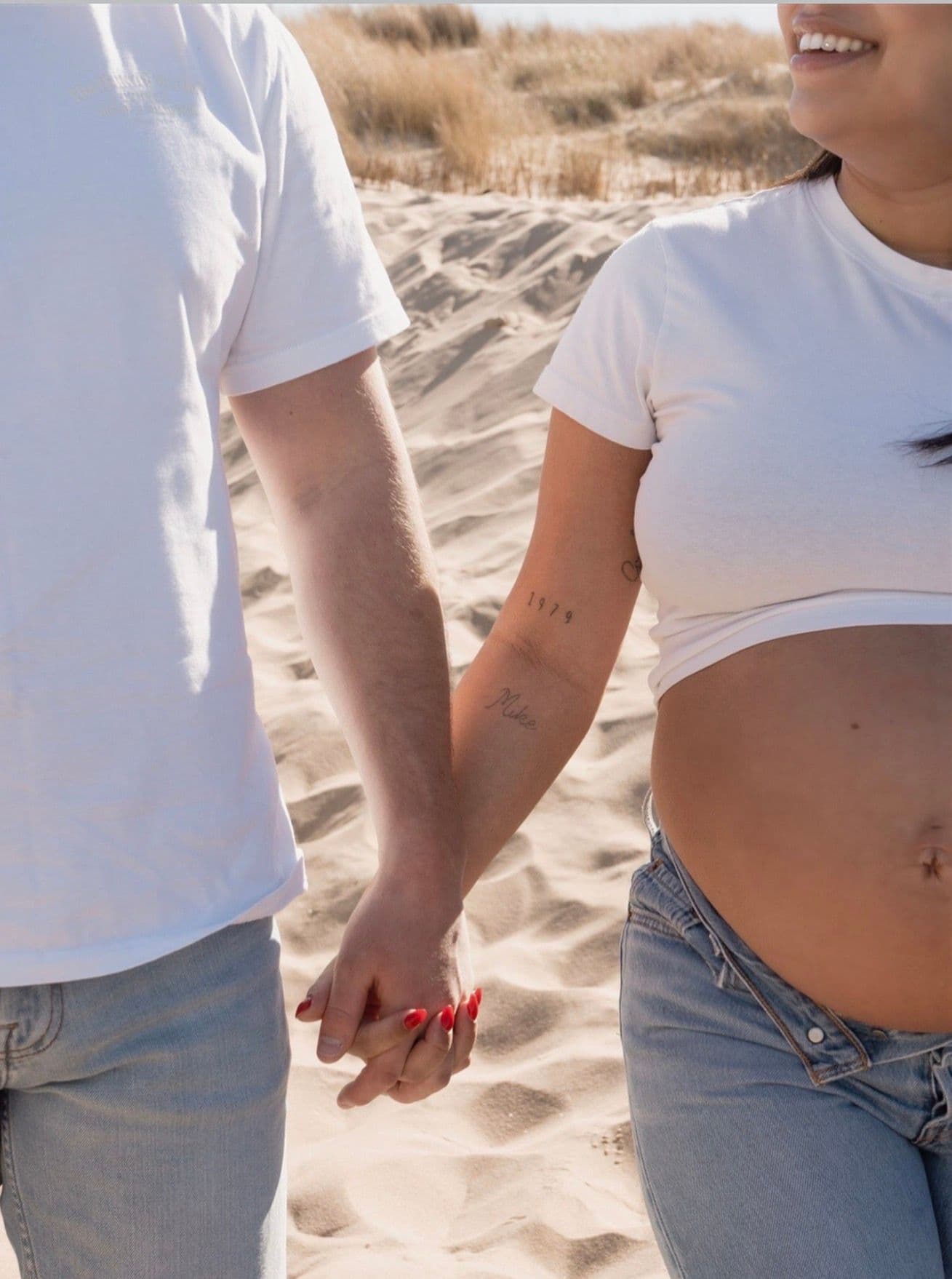 Aanstaande ouders, hand in hand op het strand.